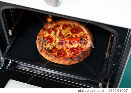 Baked pizza with sausage and pepper in the oven in the kitchen. Cooking. Restaurant advertising banner. Italian, spicy. Baked pizza with sausage and pepper in the oven in the kitchen. Cooking. Restaurant advertising banner. Italian, spicy. 125141067
