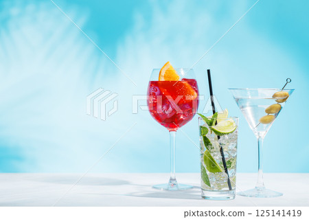 A variety of cocktails arranged on a table against a light blue background 125141419