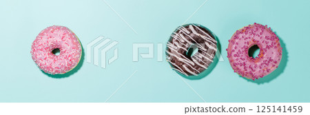 A colorful assortment of vibrant donuts with various toppings arranged on a blue 125141459