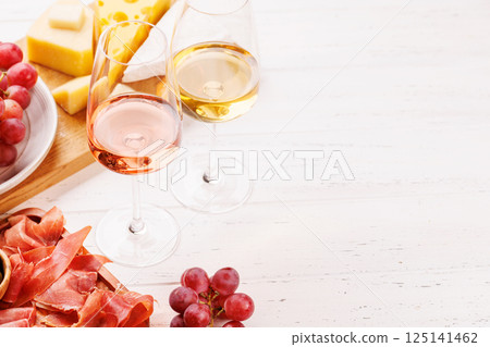 A delectable arrangement of various cheeses, fresh grapes, prosciutto and wine 125141462
