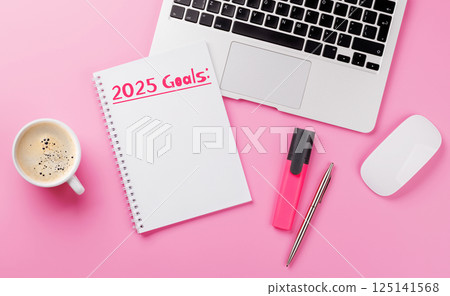 Modern pink desk with laptop, coffee, stationery, and a notepad titled 2025 Goals Modern pink desk with laptop, coffee, stationery, and a notepad titled 2025 Goals 125141568