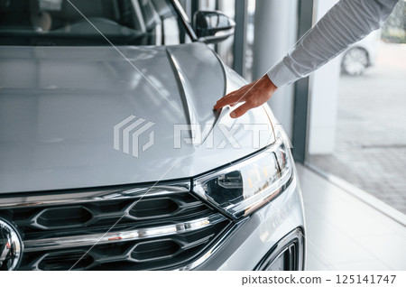 Young man in white clothes is in the car dealership 125141747