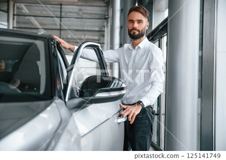 Young man in white clothes is in the car dealership 125141749