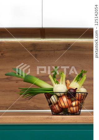 A basket, a vase with different types of onions in the kitchen. Healthy healthy food. Vegetables. Shallot. Leek. Fennel. 125142054