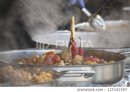 Steaming plov simmers in large metal pots, a flavorful Central Asian rice dish with vegetables. 125142397