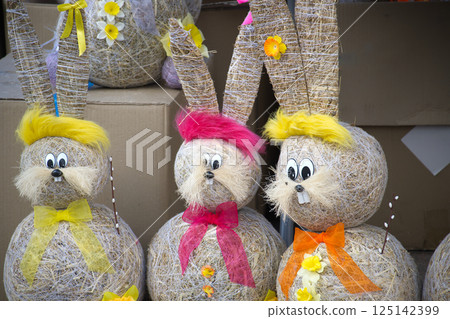 Three adorable straw Easter bunnies with bright hair and bows bring springtime cheer, festive charm. Three adorable straw Easter bunnies with bright hair and bows bring springtime cheer, festive charm. 125142399
