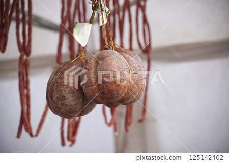 Closeup of artisanal sausages and long salami, showcasing traditional European food culture. 125142402