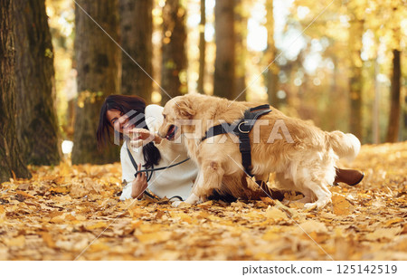 Smiling and playing. Woman on the walk with her two dogs in the autumn forest Smiling and playing. Woman on the walk with her two dogs in the autumn forest 125142519