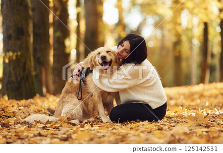 Embracing the animal. Woman is on the walk with her dog in the autumn forest at daytime Embracing the animal. Woman is on the walk with her dog in the autumn forest at daytime 125142531