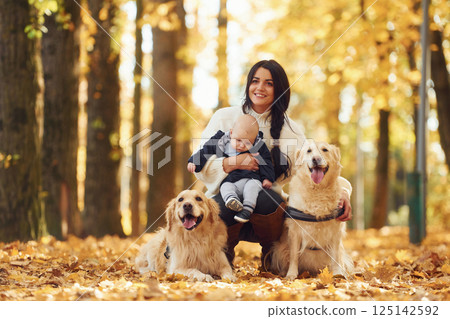 Mother with toddler and with two dogs are in the autumn forest 125142592