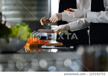 Culinary student practicing knife skills in a professional kitchen Culinary student practicing knife skills in a professional kitchen 125142752