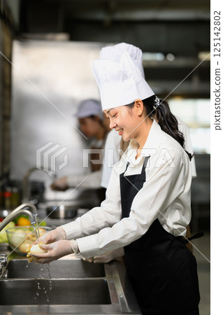 Female student washing vegetables during cooking class 125142802