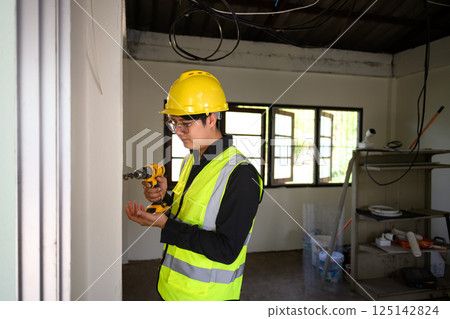 Construction worker using a drill during renovation work Construction worker using a drill during renovation work 125142824