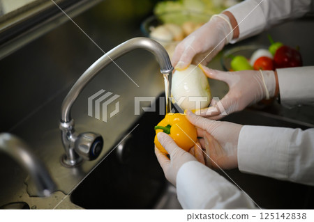 Female student washing vegetables during cooking class 125142838