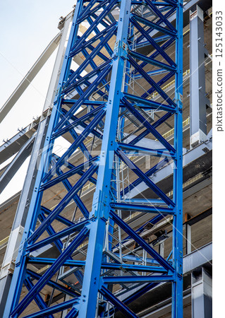 Blue Construction Crane Tower and Framework with Building in Background 125143033
