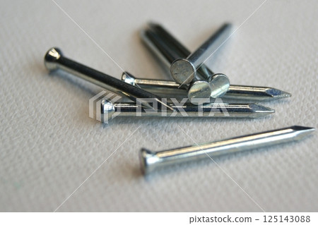 Close-up of small metal nails on a white background Close-up of small metal nails on a white background 125143088