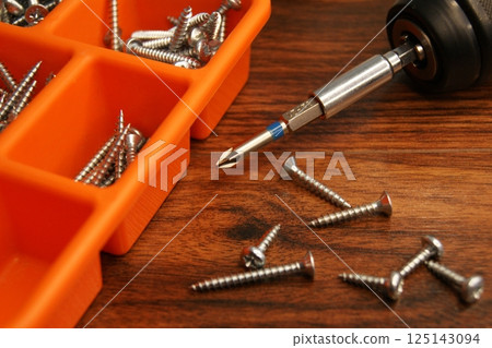 Red screw box and screwdriver on the table. Fitter's place of work. 125143094