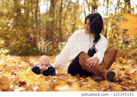Mother with her little baby son is sitting in the forest 125143131
