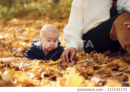Mother with her little baby son is sitting in the forest Mother with her little baby son is sitting in the forest 125143170