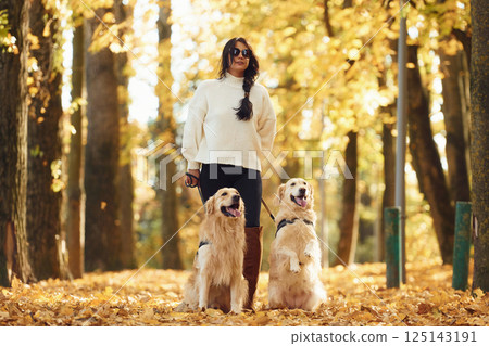 In black sunglasses. Woman on the walk with her two dogs in the autumn forest 125143191