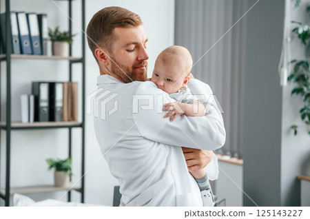 Doctor in white coat is taking care of little toddler indoors 125143227