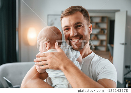 Standing with baby in hands. Father with toddler is at home, taking care of his son 125143378
