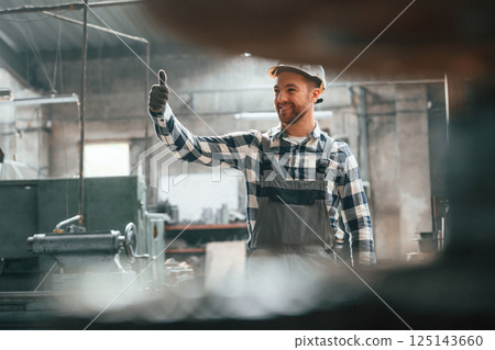 Showing thumb up. Factory male worker in uniform is indoors Showing thumb up. Factory male worker in uniform is indoors 125143660