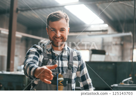 Front view. Factory male worker in uniform is indoors Front view. Factory male worker in uniform is indoors 125143703