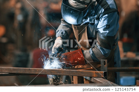 Close up view. Factory worker in protective mask is welding the iron 125143754