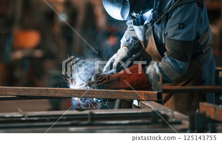Close up view. Factory worker in protective mask is welding the iron 125143755
