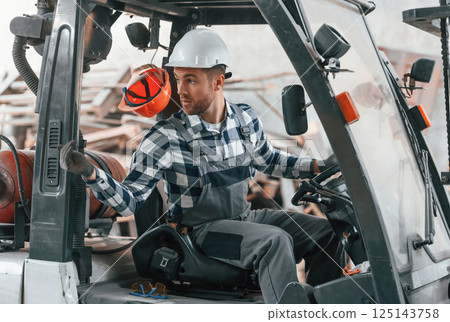 Driving the vehicle. Factory male worker in uniform is indoors 125143758