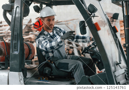 Driving the vehicle. Factory male worker in uniform is indoors 125143761