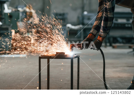 Process of welding. Factory male worker in uniform is indoors Process of welding. Factory male worker in uniform is indoors 125143802