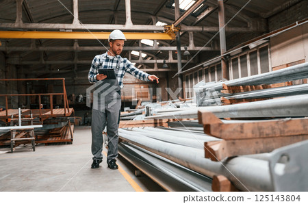 Quality control. Factory male worker in uniform is indoors 125143804