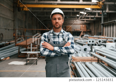 Standing with arms crossed. Factory male worker in uniform is indoors 125143831