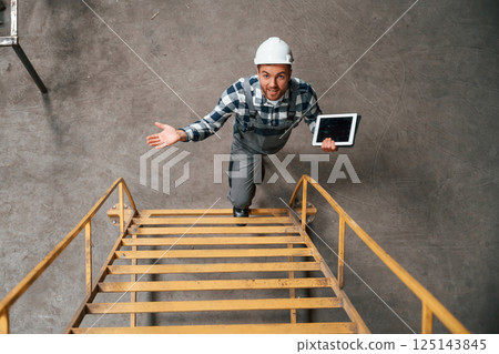 View from the top of ladder. Factory male worker in uniform is indoors View from the top of ladder. Factory male worker in uniform is indoors 125143845