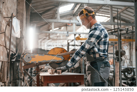 Handyman is working with factory machine. Warehouse employee in uniform is indoors Handyman is working with factory machine. Warehouse employee in uniform is indoors 125143850