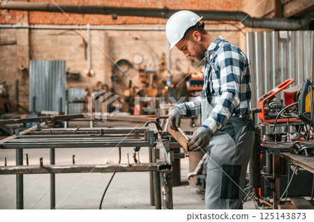 Using professional tools. Factory male worker in uniform is indoors Using professional tools. Factory male worker in uniform is indoors 125143873