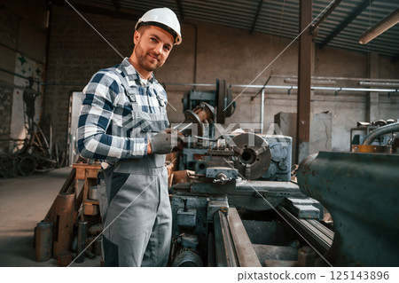 Metal processing. Factory male worker in uniform is indoors 125143896