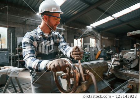Factory male worker in uniform is indoors. In defensive glasses and hard hat 125143928