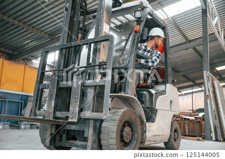 Inside of the forklift. Factory male worker in uniform is indoors Inside of the forklift. Factory male worker in uniform is indoors 125144005