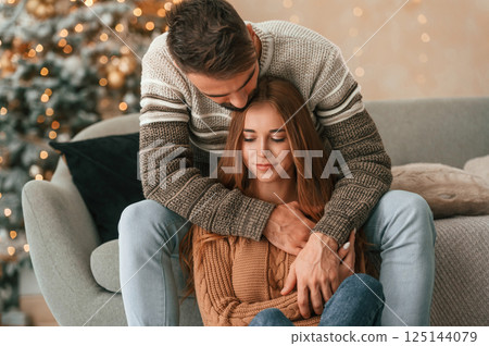 Woman is sitting. Lovely young couple are celebrating New Year at home 125144079