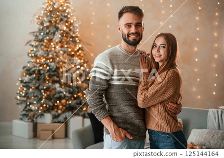 Standing and smiling. Lovely young couple are celebrating New Year at home 125144164