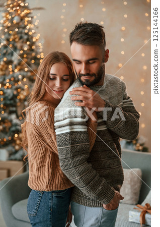 Woman is embracing the man from behind. Lovely young couple are celebrating New Year at home Woman is embracing the man from behind. Lovely young couple are celebrating New Year at home 125144166