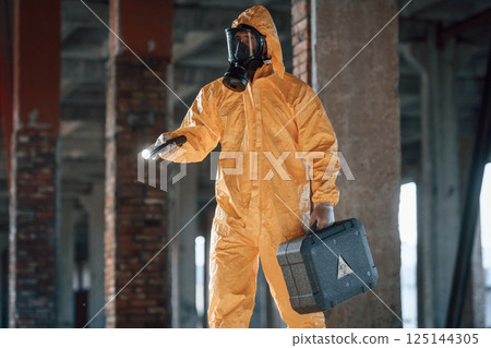 Man dressed in chemical protection suit in the ruins of the post apocalyptic building Man dressed in chemical protection suit in the ruins of the post apocalyptic building 125144305