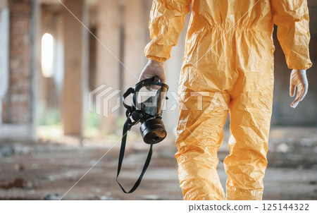 Respirator in hand. Man dressed in chemical protection suit in the ruins of the post apocalyptic building Respirator in hand. Man dressed in chemical protection suit in the ruins of the post apocalyptic building 125144322
