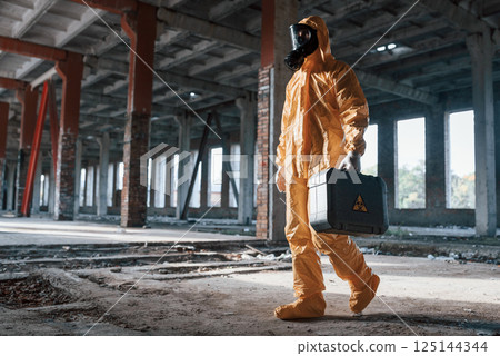 View from the side. Man dressed in chemical protection suit in the ruins of the post apocalyptic building View from the side. Man dressed in chemical protection suit in the ruins of the post apocalyptic building 125144344