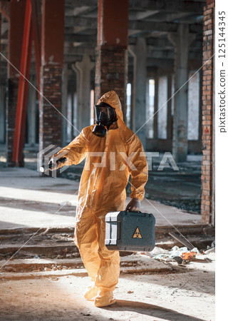 Man dressed in chemical protection suit in the ruins of the post apocalyptic building Man dressed in chemical protection suit in the ruins of the post apocalyptic building 125144345
