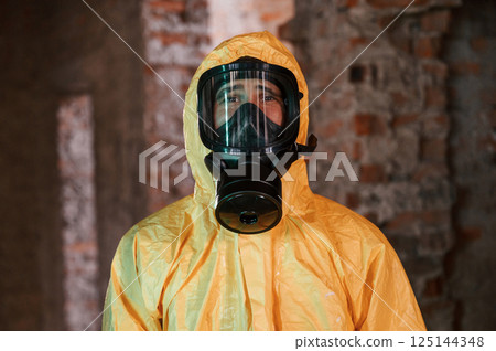 In respirator, portrait. Man dressed in chemical protection suit in the ruins of the post apocalyptic building 125144348