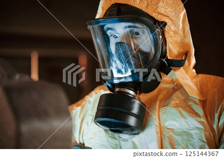Frightened scientist is with radioactive materials. Man dressed in chemical protection suit in the ruins of the post apocalyptic building 125144367